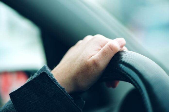 Female hand on car steering wheel